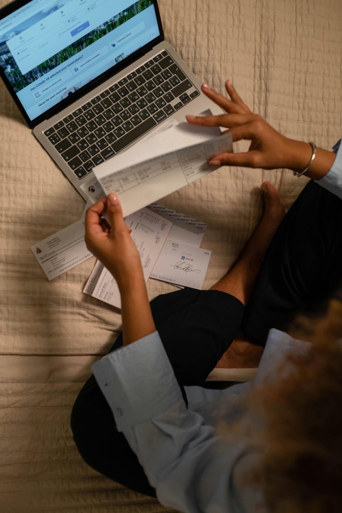 pexels-photo-6862449-6862449 Woman holding checks while managing finances on a laptop, showing online banking on the screen.